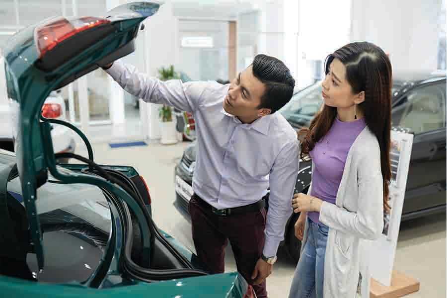 asian couple checking trunk of car for comparison and research