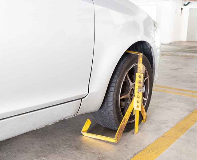Car wheel clamped for illegal parking violation at car park