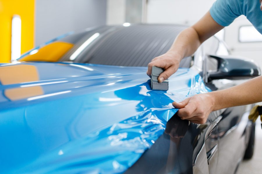 car mechanic wrapping car with car vinyl wrap