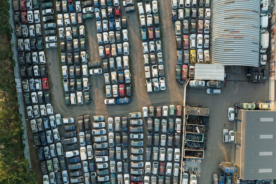 Aerial view of big parking lot of junkyard with rows of discarded broken cars. Recycling of old vehicles Aerial view of big parking lot of junkyard with rows of discarded broken cars. Recycling of old vehicles.