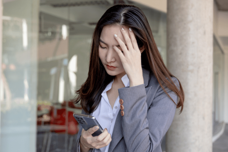 A stressed young woman with a gray suit checking her phone