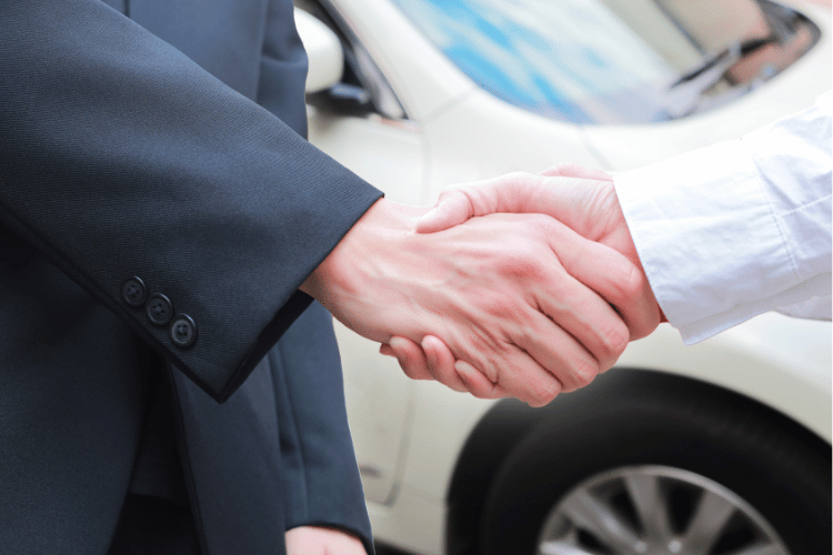 Closeup of two men handshake at car dealership
