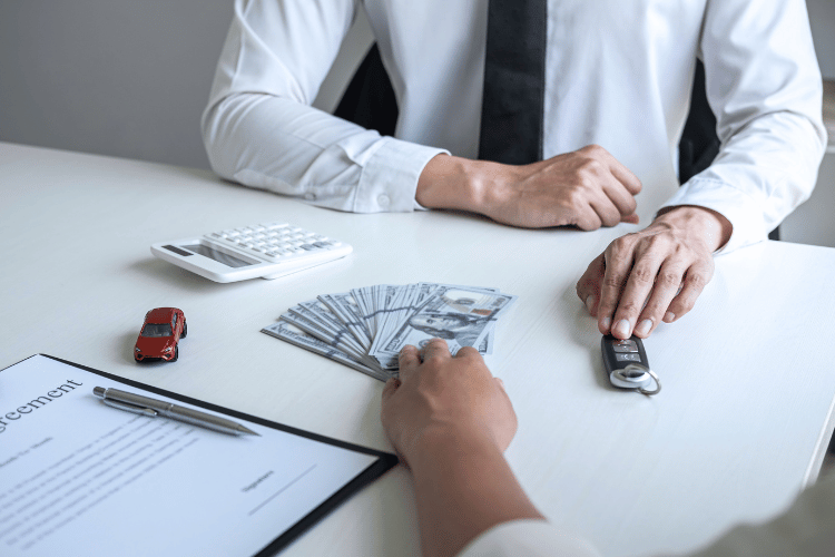 Salesman giving car key to woman exchange for cash payment
