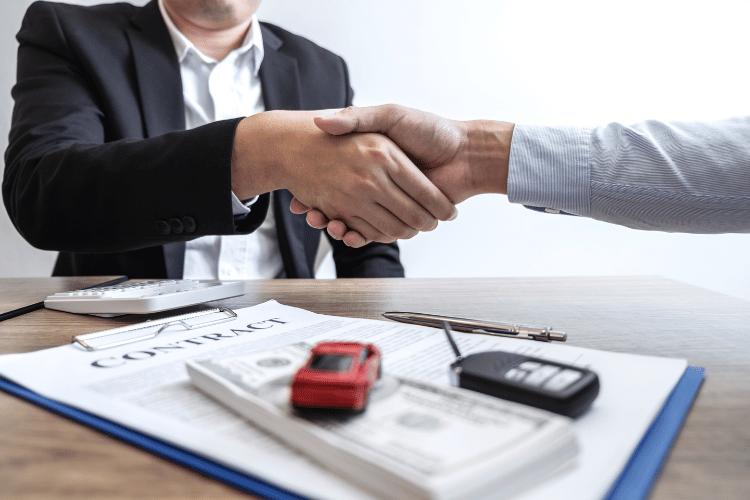 Two men handshaking for a car-selling deal